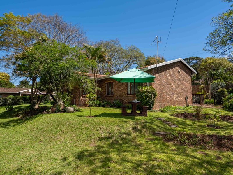 A view of the rear exterior of the townhouse, featuring a face brick facade, tiled roof, and a well-maintained garden area.
