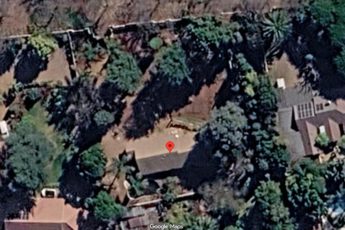 An aerial satellite view of a residential property plot featuring established trees and boundary walls.