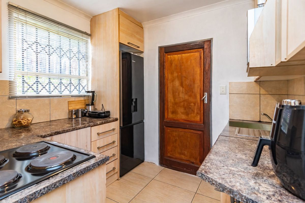 Functional kitchen featuring laminate countertops, built-in cabinetry, electric hob, and tiled flooring, offering a practical layout for daily meal preparation.