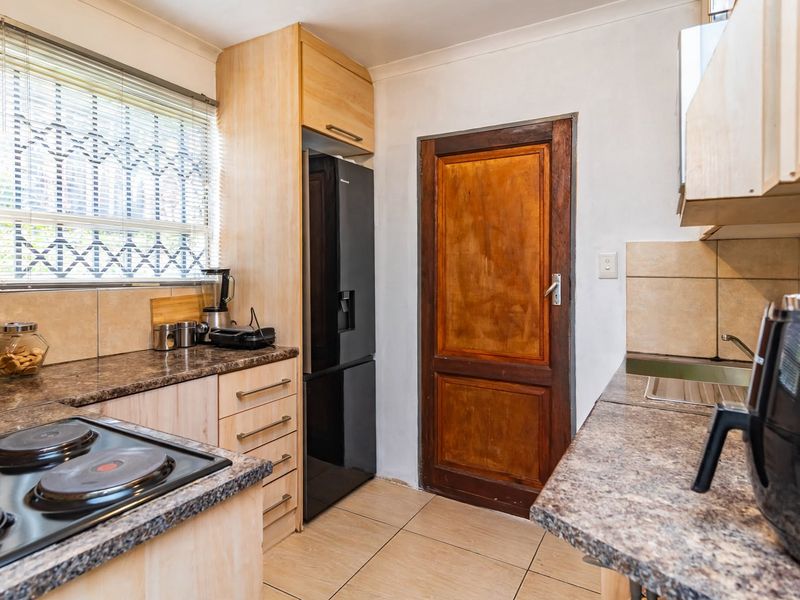 Functional kitchen featuring laminate countertops, built-in cabinetry, electric hob, and tiled flooring, offering a practical layout for daily meal preparation.