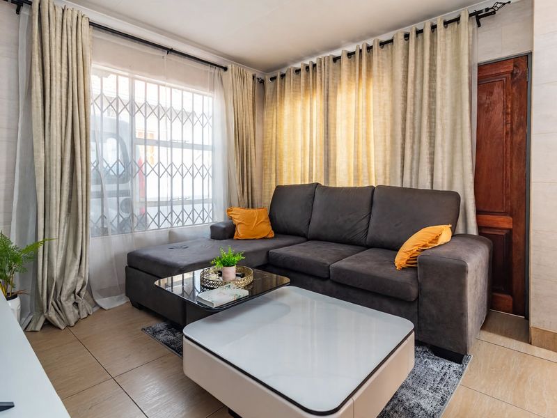 A comfortable living room featuring tiled flooring, a security gate on the window, and a solid timber door.