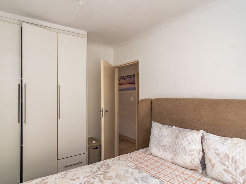 A functional bedroom featuring a built-in wardrobe with modern handles and neutral wall finishes.