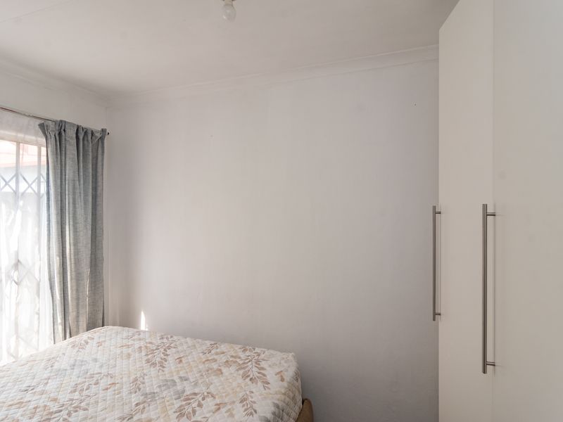 A functional bedroom featuring a built-in wardrobe and a window fitted with a security gate.