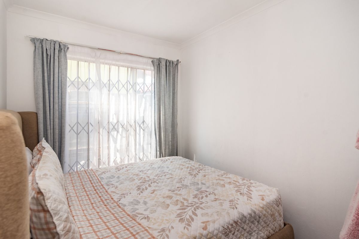 A functional bedroom featuring a sliding door with an integrated security gate, providing natural light and access to the exterior.