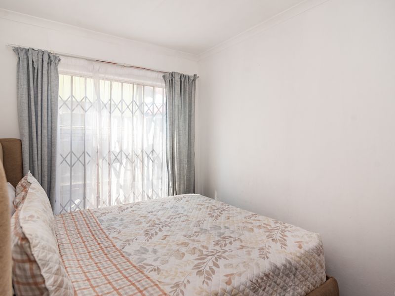 A functional bedroom featuring a sliding door with an integrated security gate, providing natural light and access to the exterior.