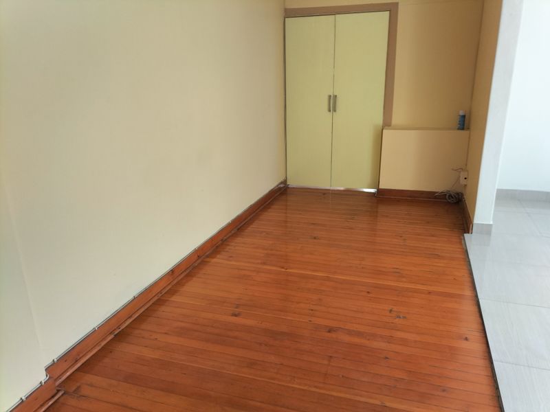 An empty bedroom featuring polished timber flooring and a built-in cupboard with light-colored doors.