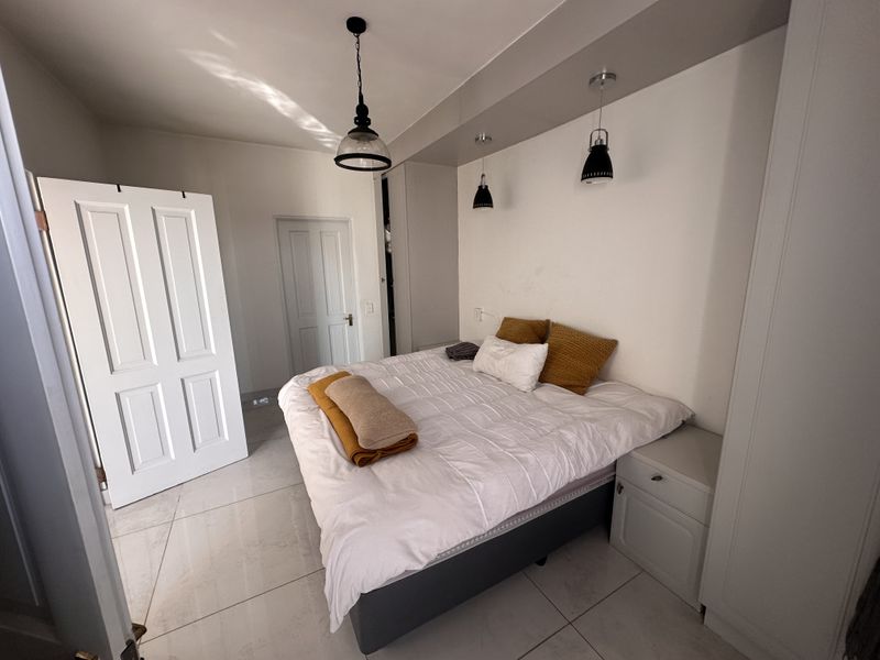 A well-maintained bedroom featuring tiled flooring, built-in cupboards, and modern pendant lighting set within a recessed bulkhead.
