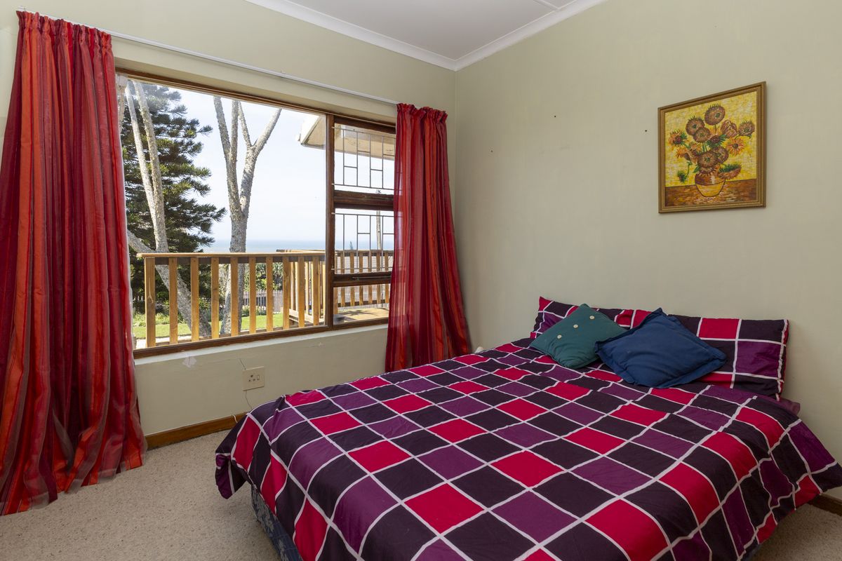 A bedroom featuring a large window with natural light, carpeted flooring, and views of the surrounding landscape.