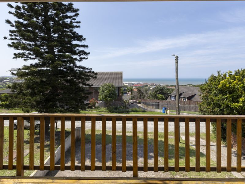 Elevated view overlooking the surrounding neighborhood and distant coastline, framed by a wooden balustrade.