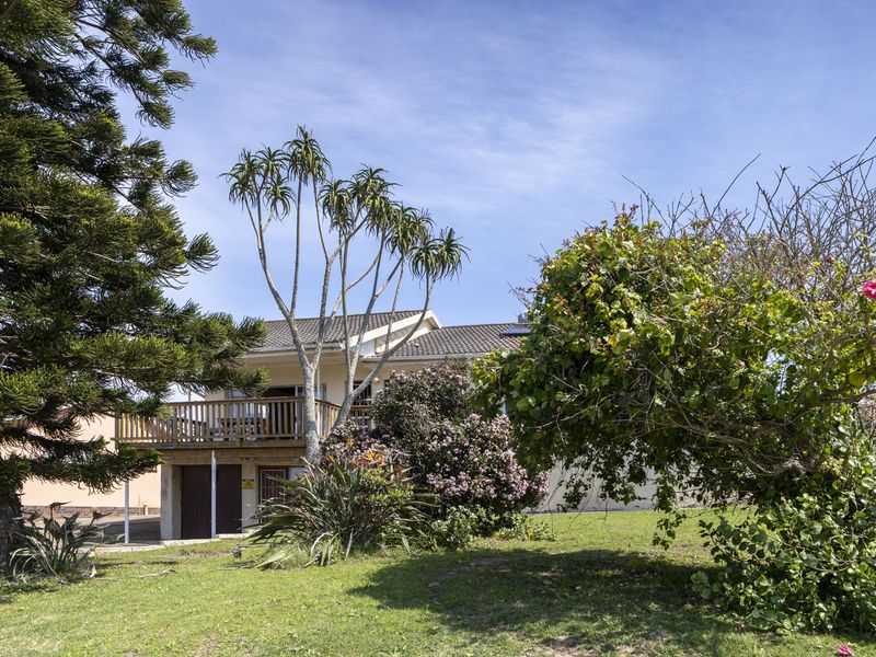 Rear view of the house featuring a wooden balcony, tiled roof, and established garden area.