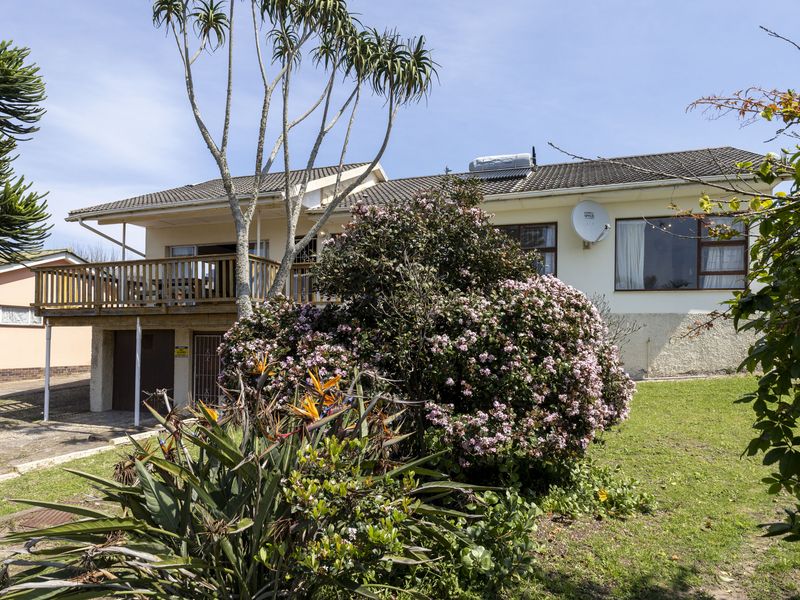 Rear view of the house featuring a raised wooden deck, landscaped garden, and solar water heating system installed on the tiled roof.