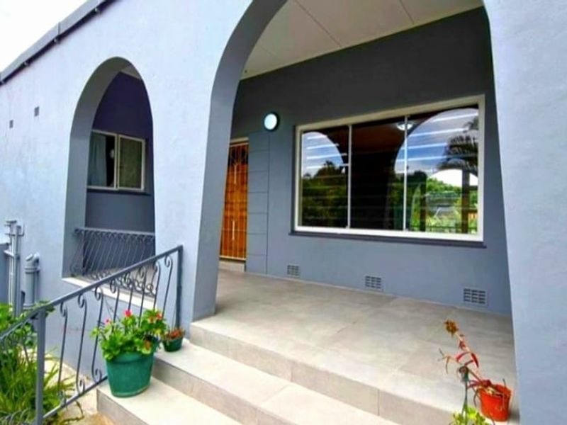 A well-maintained front entrance featuring a covered porch with arched architectural details, tiled flooring, and a secure entrance.