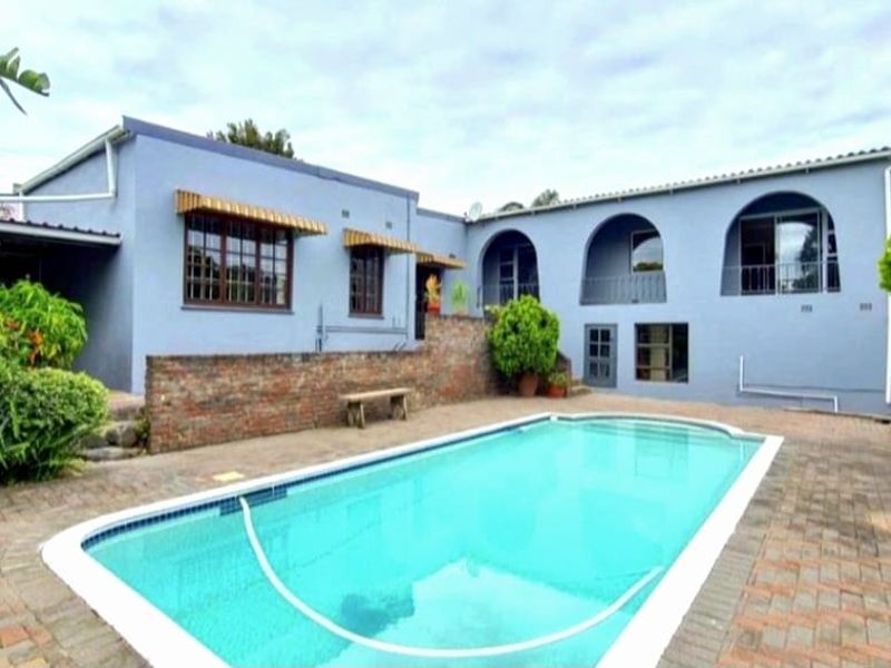 Rear exterior view featuring a swimming pool, brick paved patio area, and a two-story house with arched balcony details.