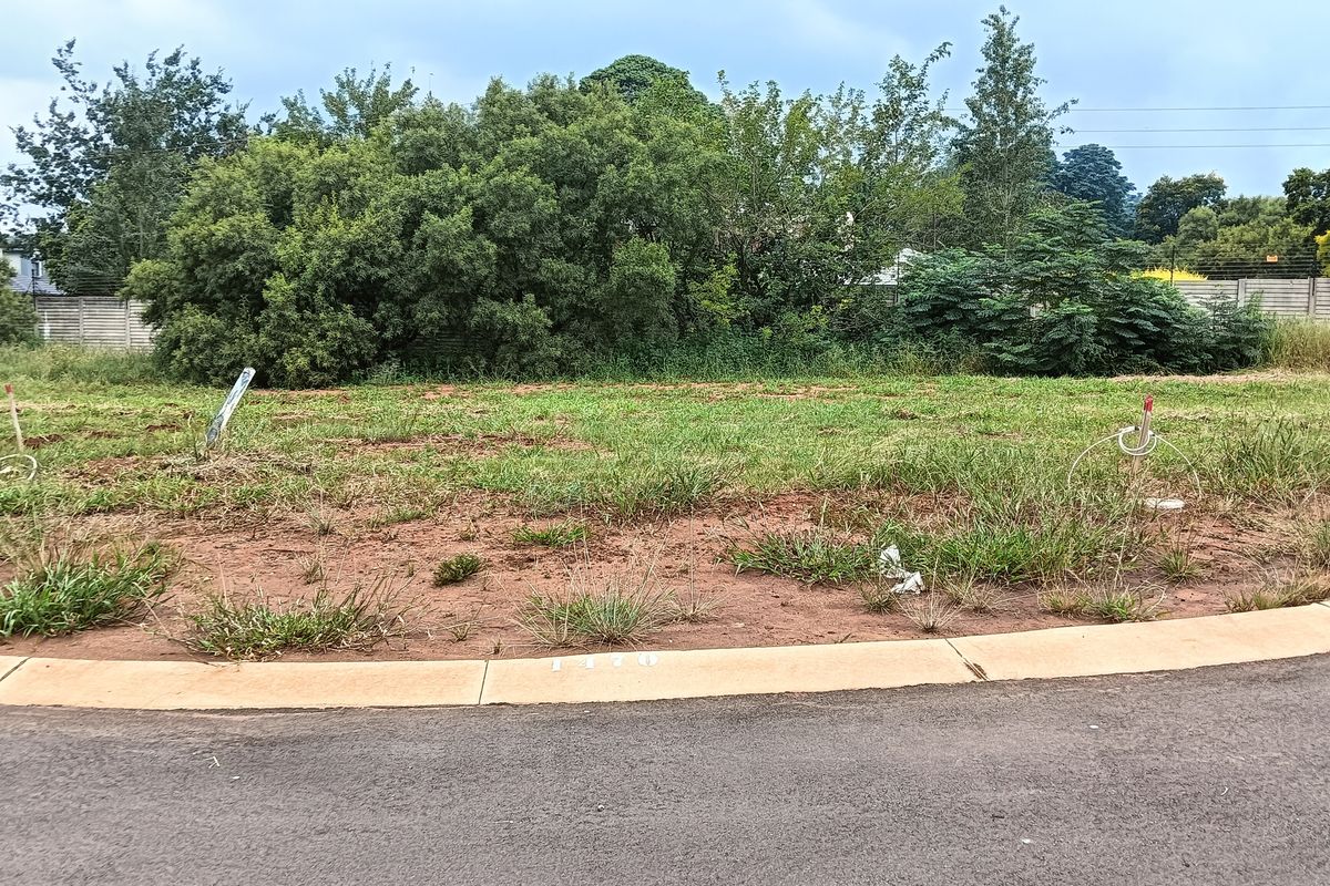 A vacant residential plot featuring a level grass surface, concrete curb, and established boundary wall, ready for development.