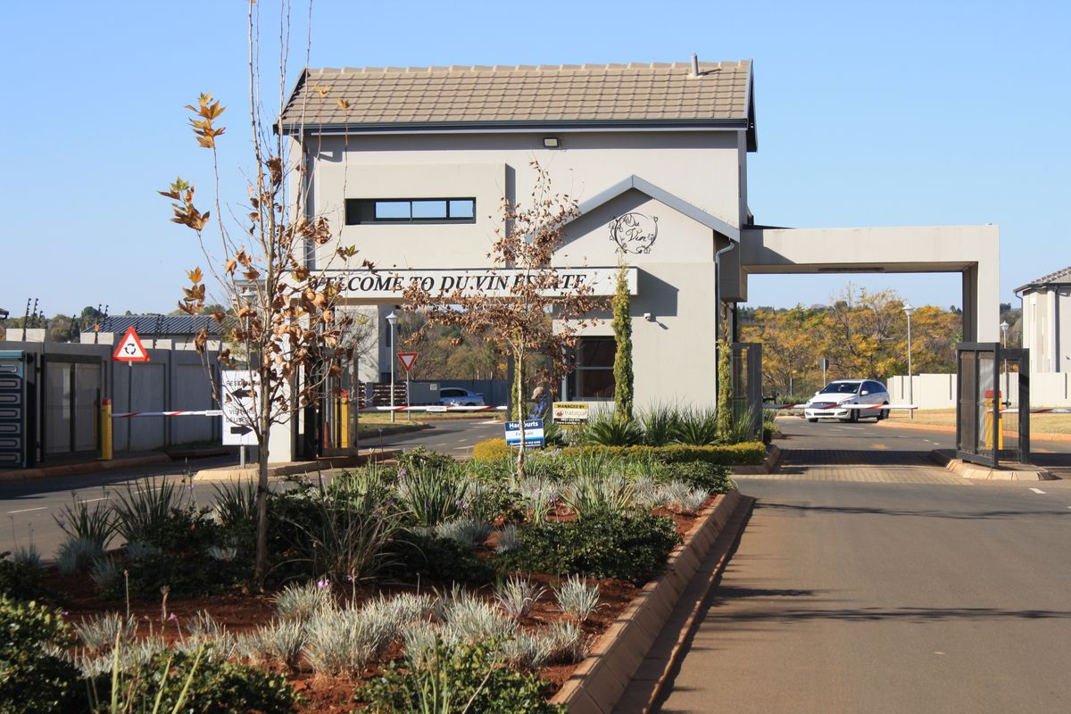 The entrance to Du Vin Estate featuring a well-maintained security gatehouse, boom gate access, and landscaped garden beds.