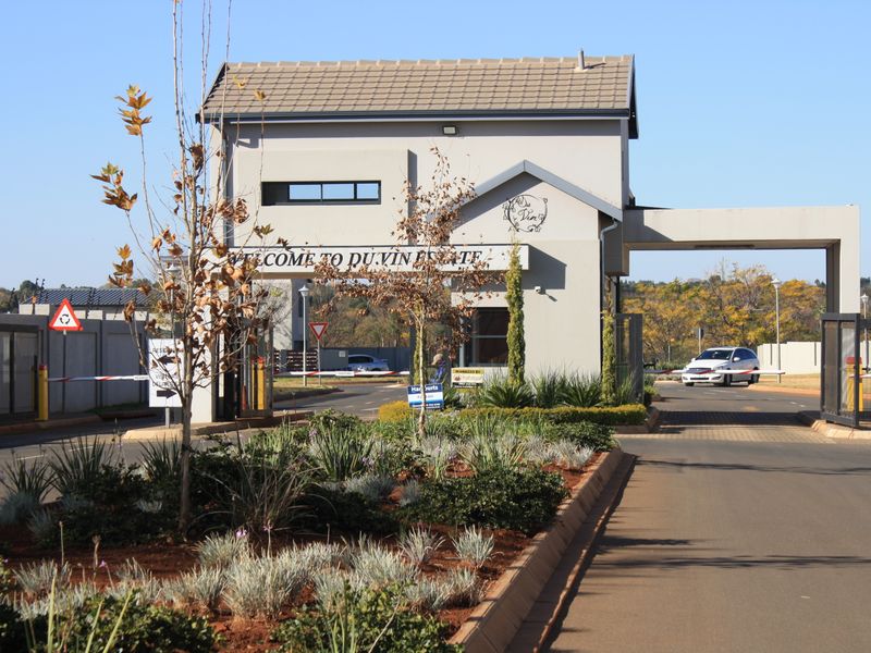 The entrance to Du Vin Estate featuring a well-maintained security gatehouse, boom gate access, and landscaped garden beds.