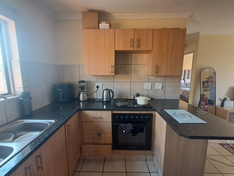 A functional kitchen featuring laminate cabinetry, granite countertops, a built-in oven with electric hob, and tiled backsplash, offering a practical layout for daily use.