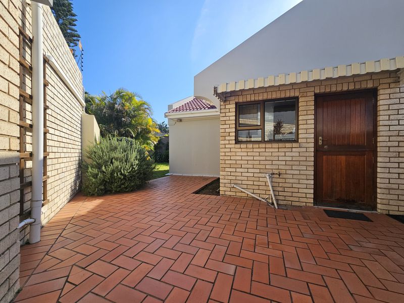 A private rear courtyard featuring durable brick paving, a timber entrance door, and a functional awning, providing a low-maintenance outdoor space.