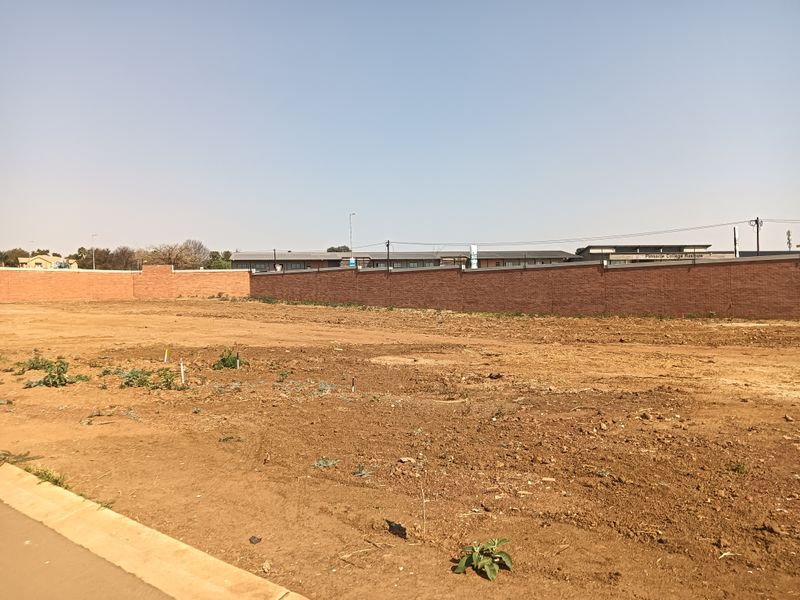 A vacant residential plot featuring a level surface and a perimeter brick boundary wall, ready for development.