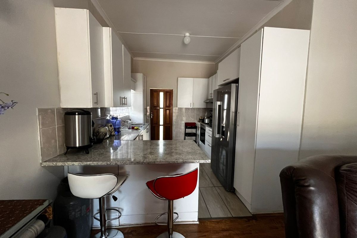 A functional kitchen featuring white cabinetry, laminate countertops, a breakfast bar, and built-in appliances, providing a practical layout for daily meal preparation.