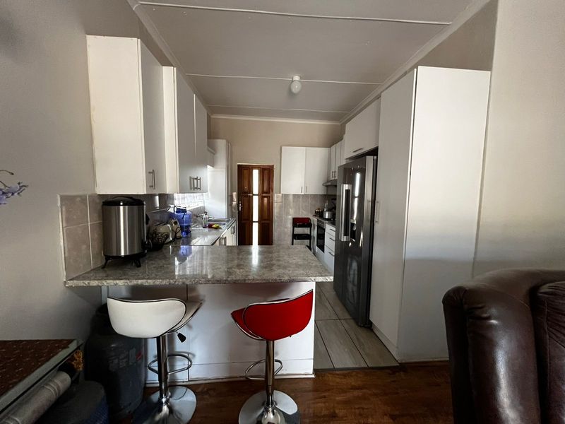 A functional kitchen featuring white cabinetry, laminate countertops, a breakfast bar, and built-in appliances, providing a practical layout for daily meal preparation.