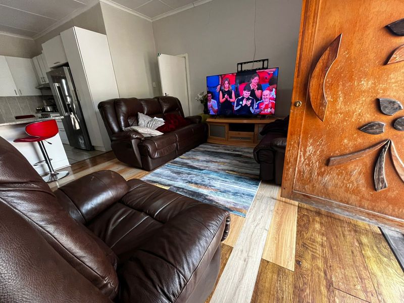 Open plan living area featuring laminate flooring and an adjacent kitchen with white cabinetry.