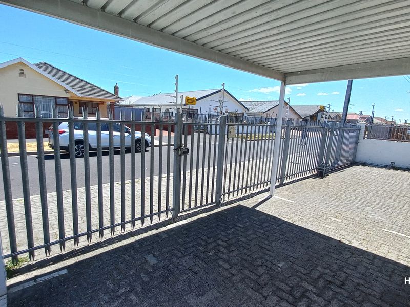 A covered carport area featuring paved flooring and secure metal perimeter fencing with an electric fence system.