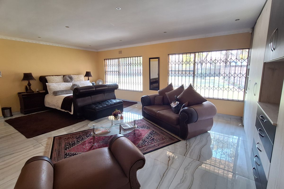 Spacious bedroom featuring tiled flooring, built-in cupboards, recessed downlighting, and security gates on the windows.