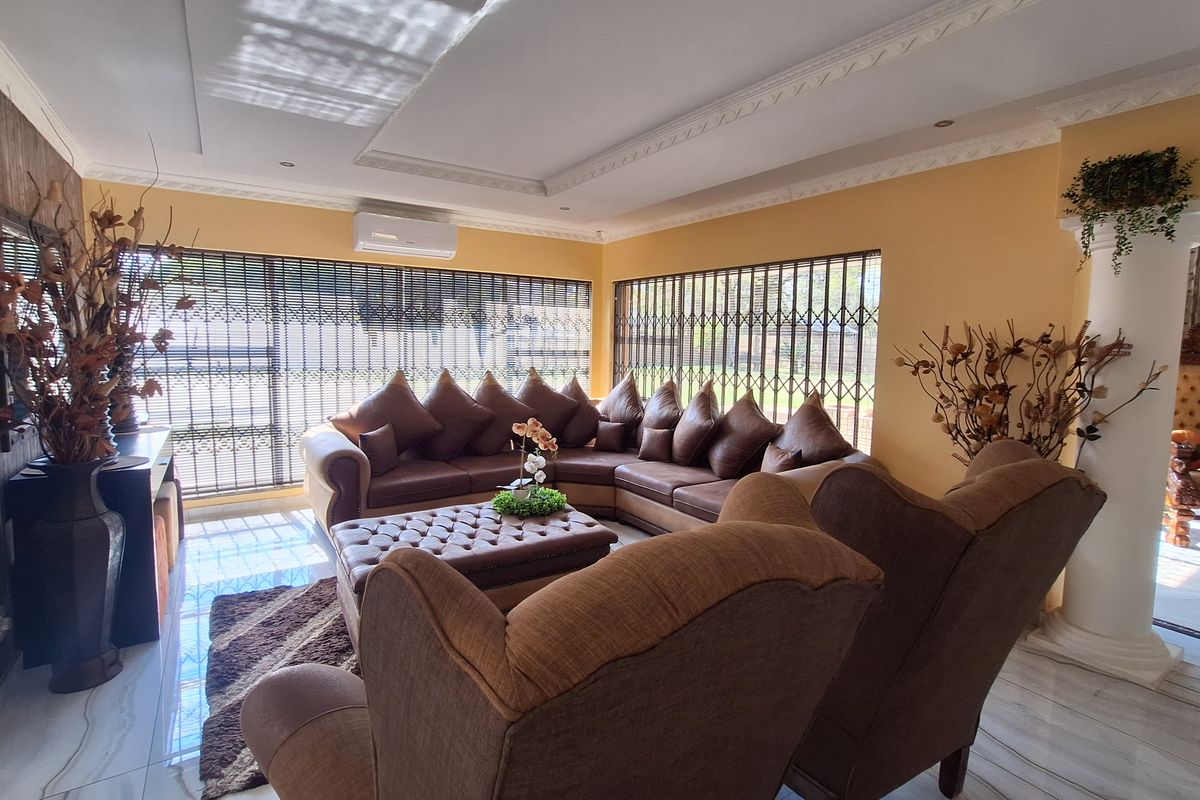 Spacious living room featuring tiled flooring, decorative ceiling molding, a split-system air conditioner, and large windows secured with metal security gates.