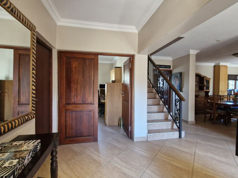 Welcoming entrance hall featuring tiled flooring, solid timber doors, and a staircase with a decorative wrought iron balustrade leading to the upper level.