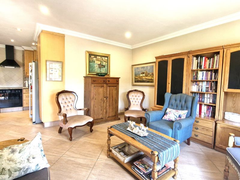 Spacious open-plan living area featuring tiled flooring, recessed lighting, and a functional kitchen with built-in cabinetry and integrated appliances.
