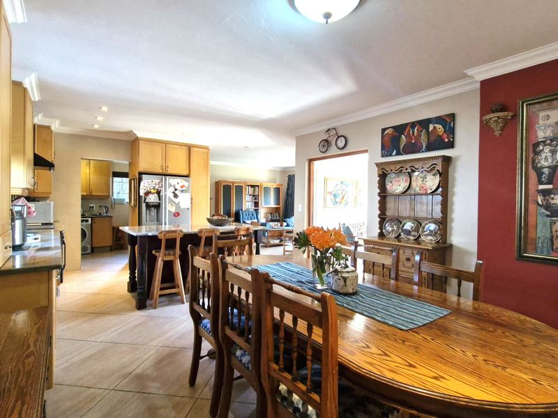 Spacious open-plan kitchen and dining area featuring tiled flooring, wooden cabinetry, and a central kitchen island, creating a functional family living space.
