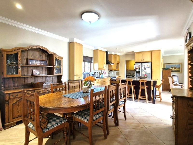 Spacious open-plan kitchen and dining area featuring light wood cabinetry, a central kitchen island, and tiled flooring throughout.