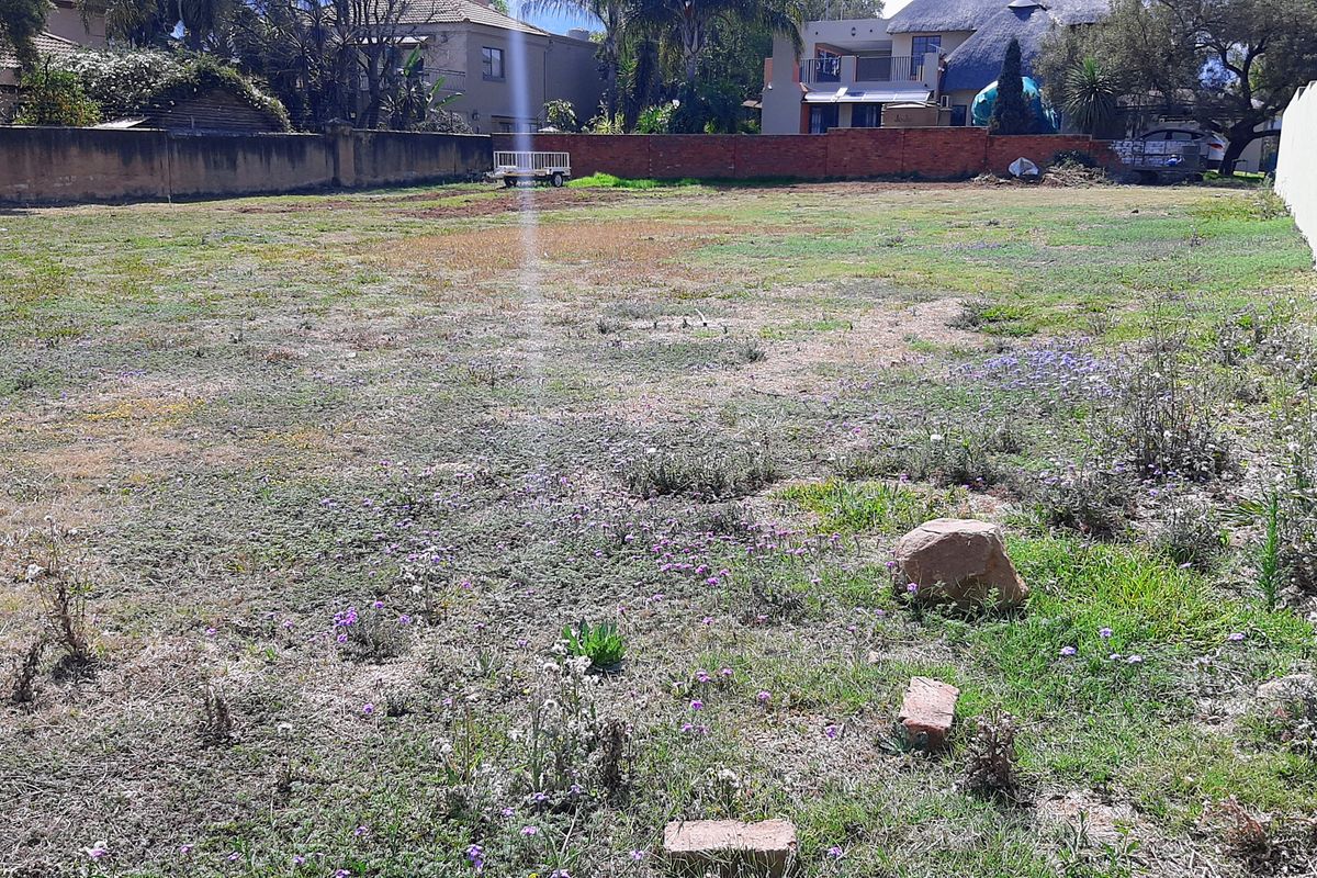 A vacant residential plot featuring a level grassed area enclosed by perimeter brick boundary walls, suitable for future development.