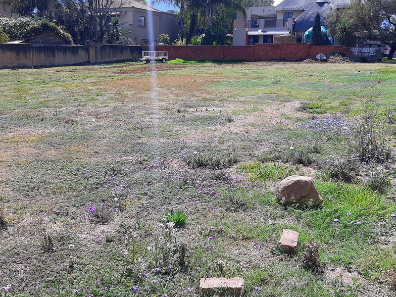A vacant residential plot featuring a level grassed area enclosed by perimeter brick boundary walls, suitable for future development.