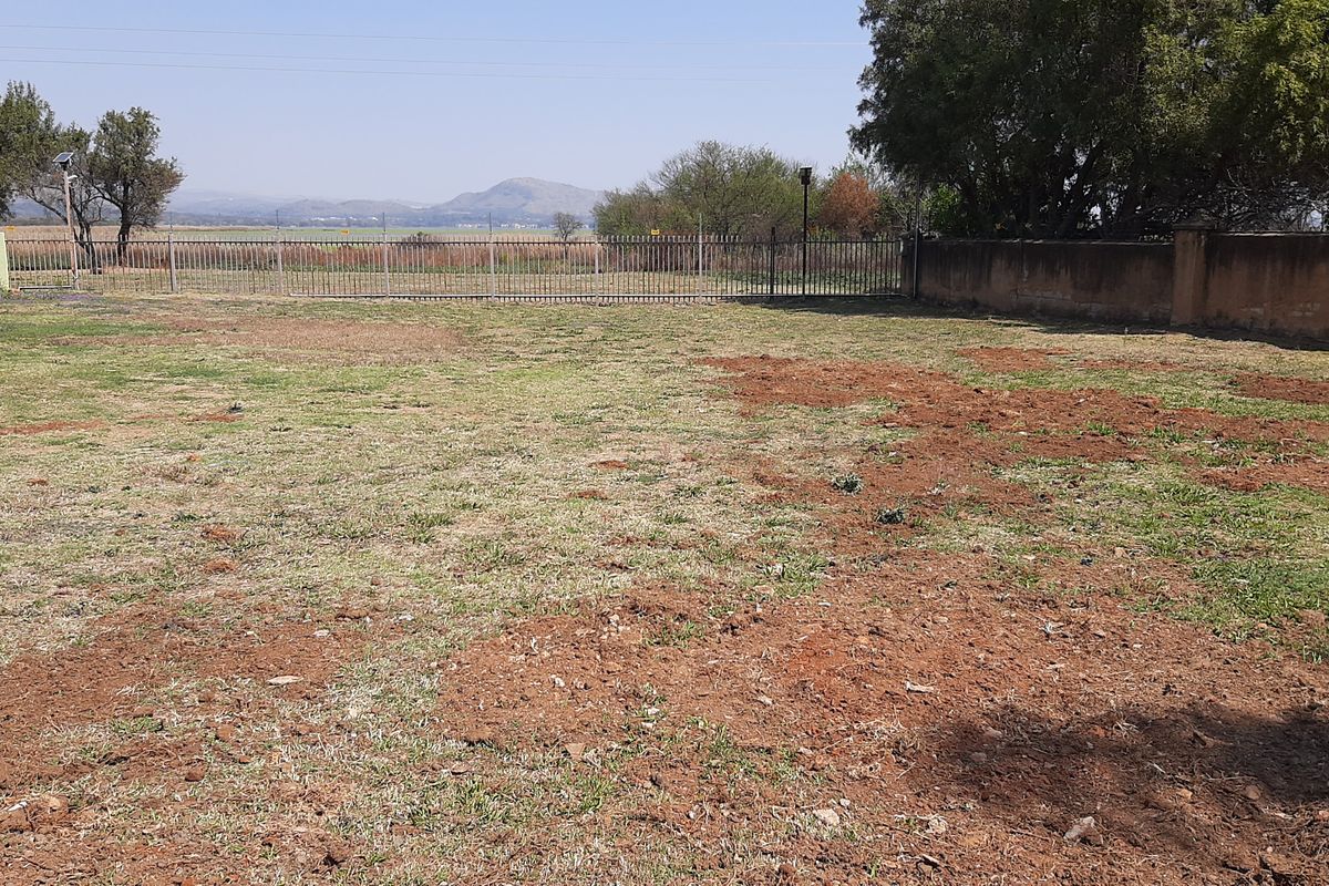 A vacant residential plot featuring perimeter fencing and boundary walls with views of the surrounding landscape.