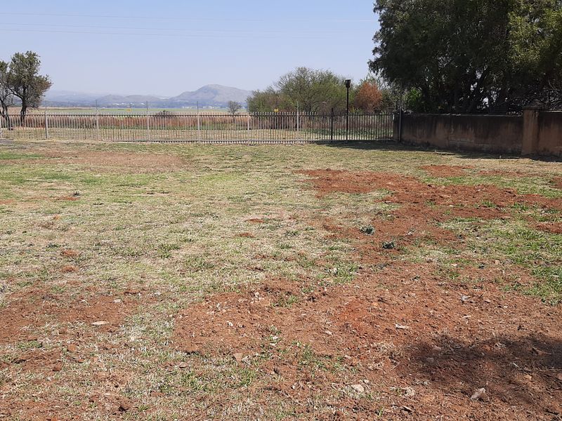 A vacant residential plot featuring perimeter fencing and boundary walls with views of the surrounding landscape.