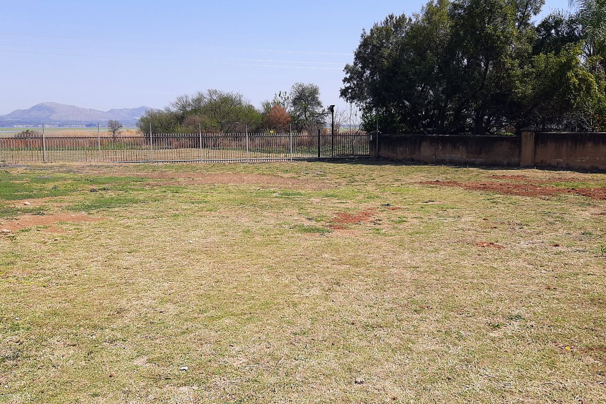 A spacious, level residential plot featuring perimeter fencing and a boundary wall, offering potential for landscaping or future development.
