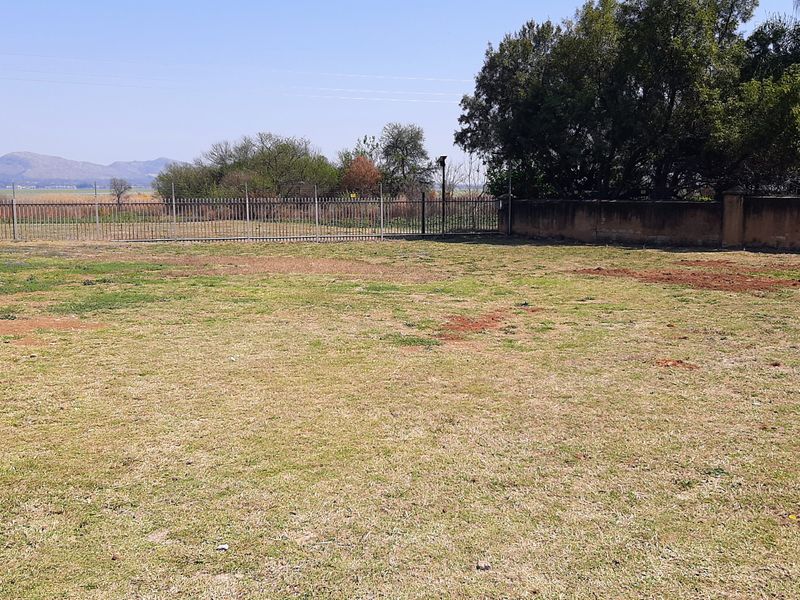 A spacious, level residential plot featuring perimeter fencing and a boundary wall, offering potential for landscaping or future development.