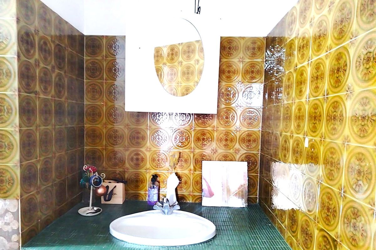 A bathroom vanity area featuring vintage patterned wall tiles, a built-in basin, and a wall-mounted medicine cabinet.