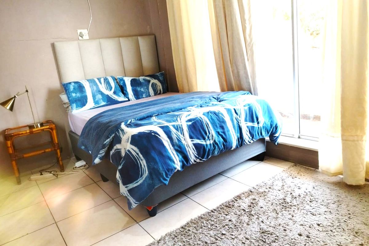 A bedroom featuring tiled flooring and a sliding glass door providing natural light, with an upholstered headboard as a focal point.