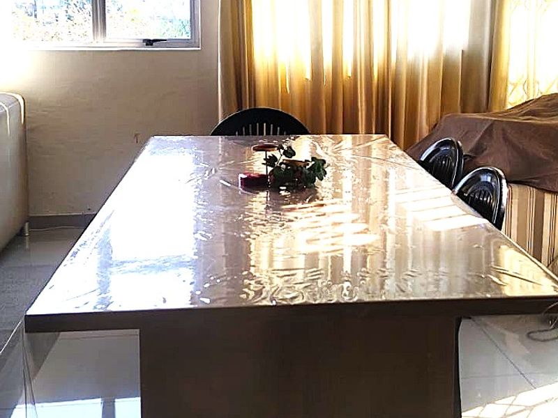 A dining room featuring tiled flooring and natural light from a large window, providing a functional space for family meals.