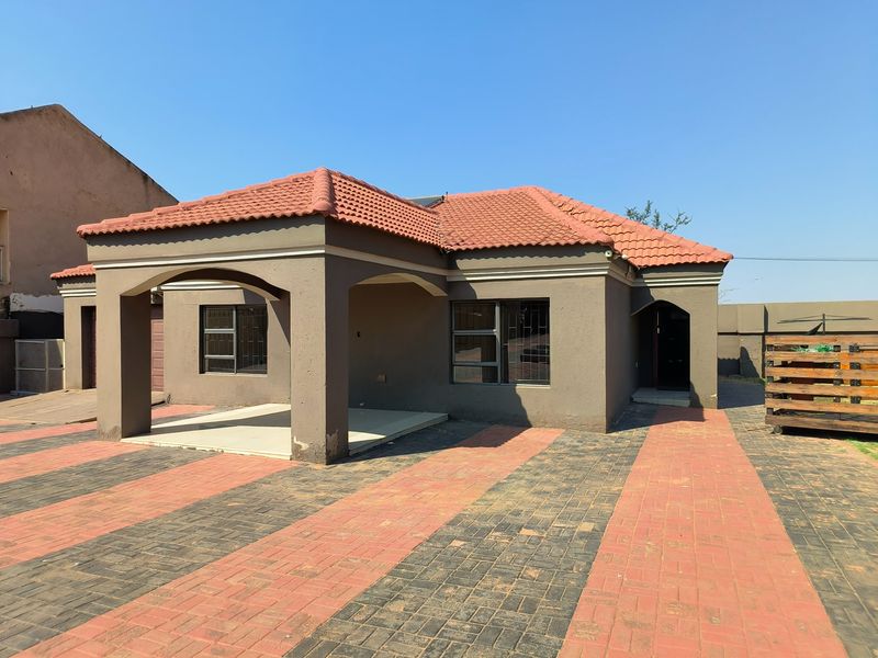 Front exterior view of a single-story house featuring a tiled roof, covered patio area, and a paved driveway.