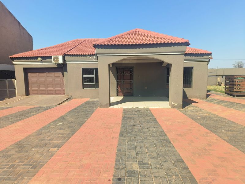 Front elevation of a single-story house featuring a tiled roof, covered entrance porch, integrated garage, and a paved driveway.