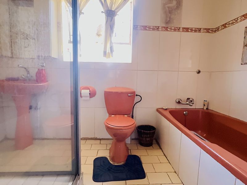A dated bathroom featuring a colored pedestal sink, toilet, and bathtub with a separate shower enclosure and tiled finishes throughout.