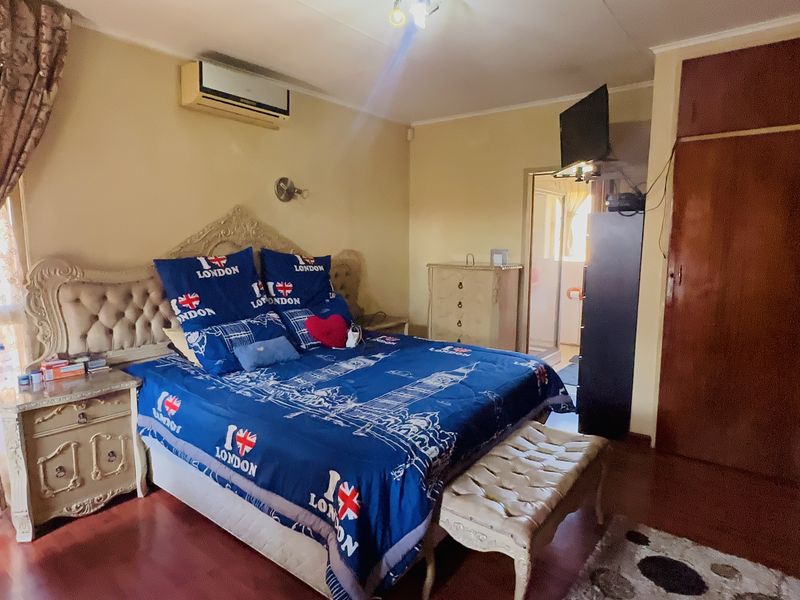 A bedroom featuring laminate flooring, a built-in wardrobe, and a wall-mounted air conditioning unit.