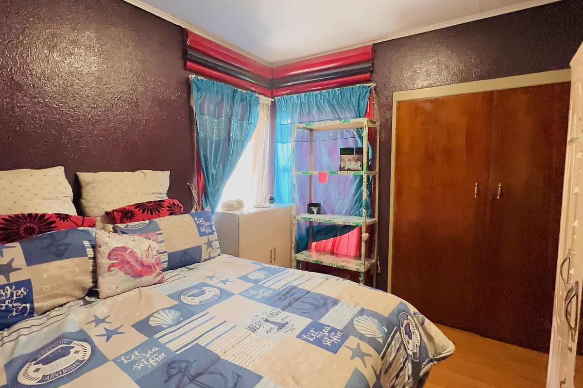 A bedroom featuring timber flooring and a built-in wardrobe with dark purple walls.