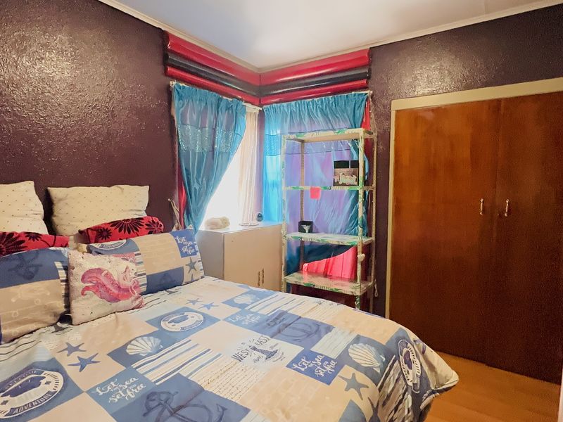 A bedroom featuring timber flooring and a built-in wardrobe with dark purple walls.