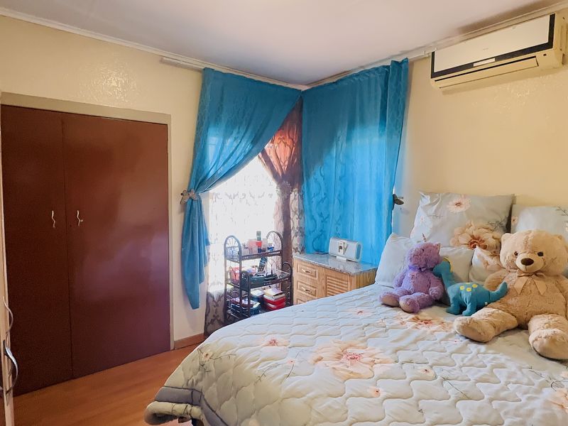 A bedroom featuring laminate flooring, a built-in wardrobe, and a wall-mounted split-system air conditioning unit.