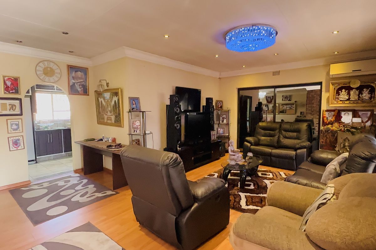 Spacious living room featuring laminate flooring, recessed lighting, and an air conditioning unit, with an arched entryway leading to the kitchen area.